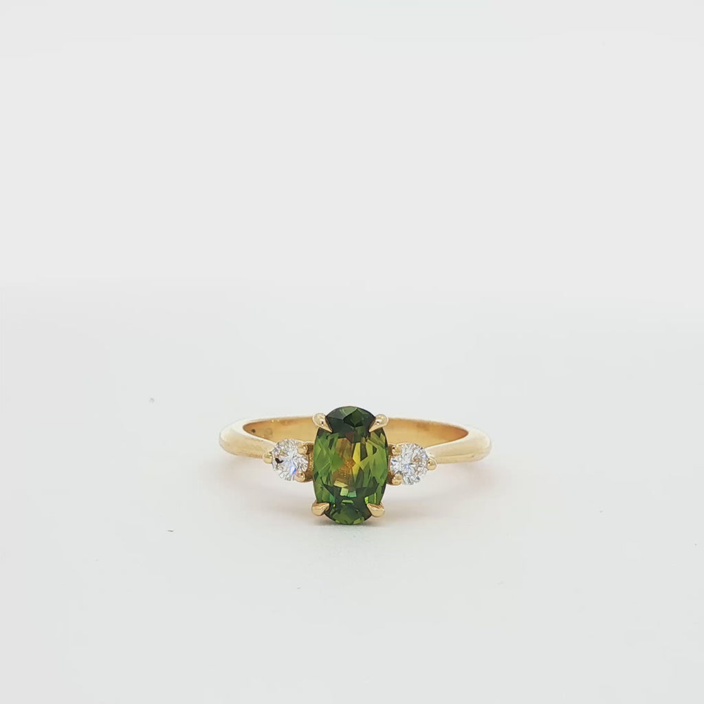 green and yellow sapphire engagement ring spinning on a turntable
