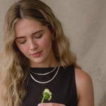 blonde model wearing two snake chains in 40cm and 45cm lengths layered, holding a flower and smiling to camera