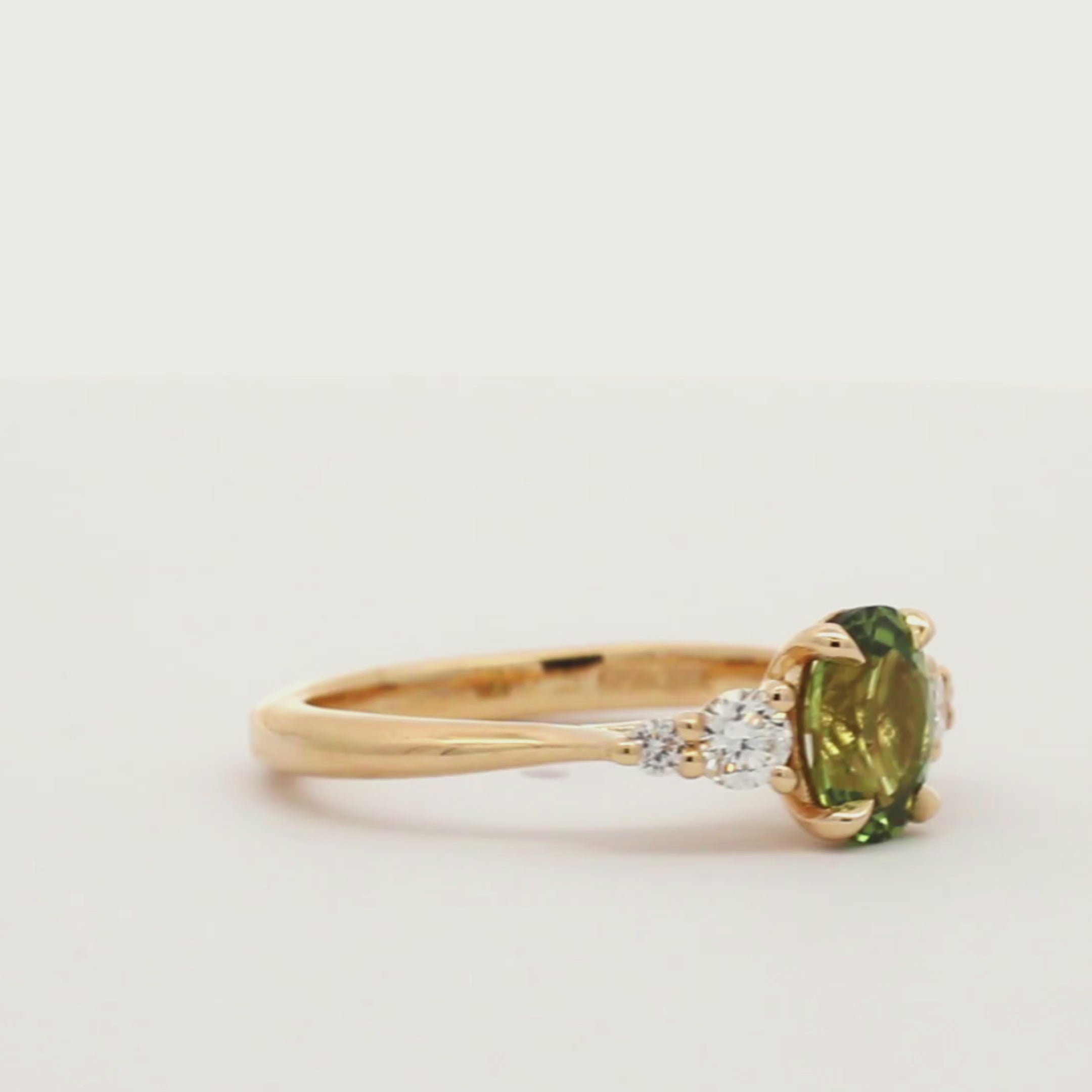 green sapphire ring with 4 diamonds spinning on a turntable