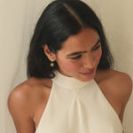 brunette bride wearing white halter neck dress and diamond sun earrings smiling to camera