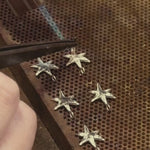 Shooting star dangle earrings being made on a jewellery workbench using pliers, wire and solder