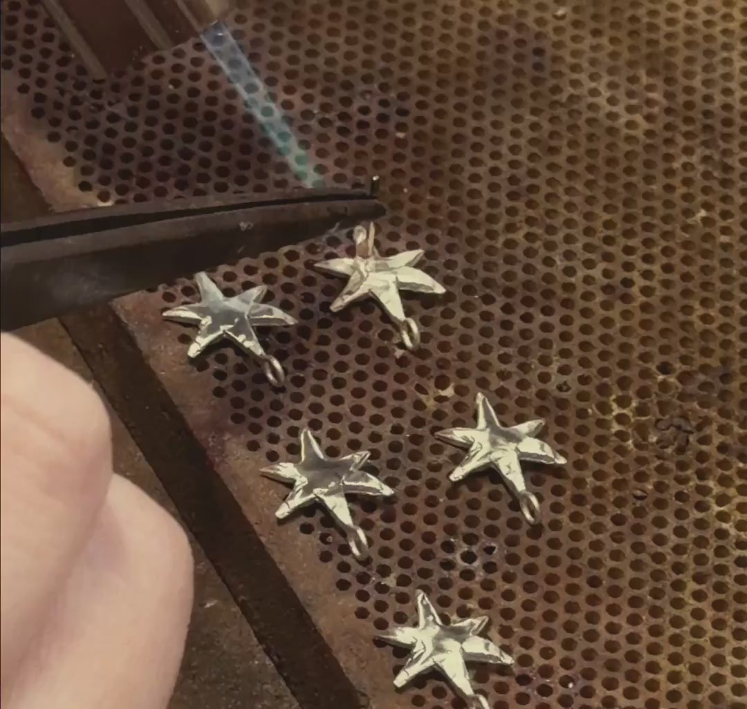 Shooting star dangle earrings being made on a jewellery workbench using pliers, wire and solder
