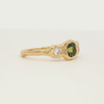 cushion cut green sapphire trilogy engagement ring with molten organic texture spinning on a turntable