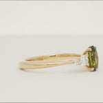 gold engagement ring with green sapphire and four tapered accent diamonds spinning on a turntable