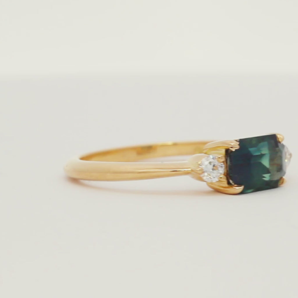 blue green sapphire engagement ring  with east-west rectangular stone and diamonds spinning on a turntable