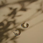 chunky silver hoops of a light yellow surface with shadows of leaves