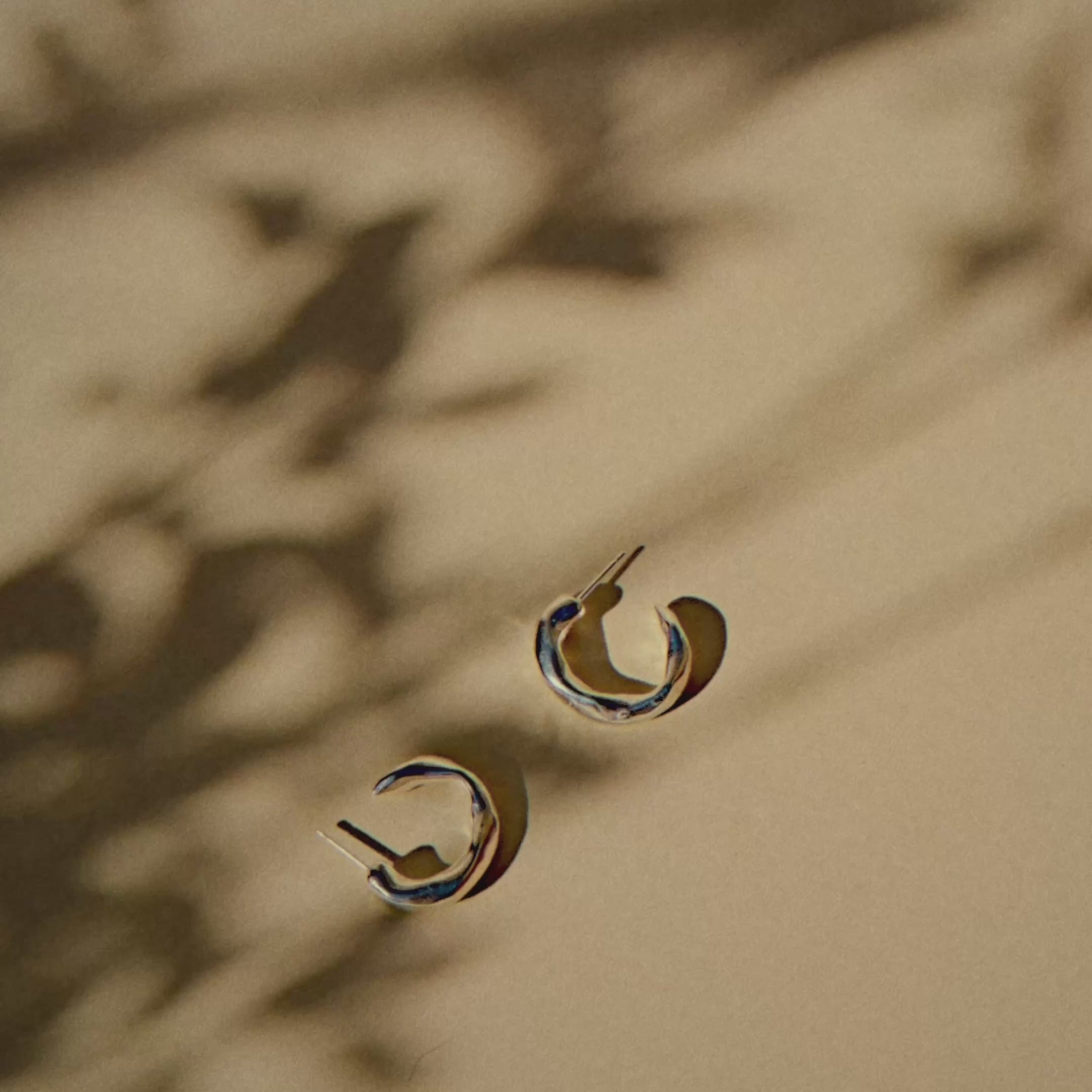 chunky silver hoops of a light yellow surface with shadows of leaves