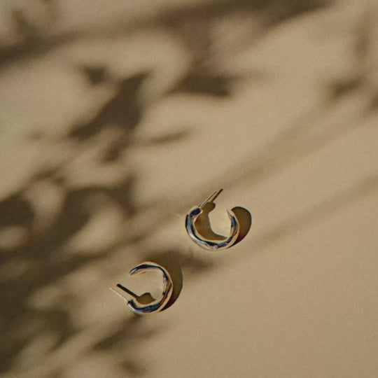 chunky silver hoops of a light yellow surface with shadows of leaves