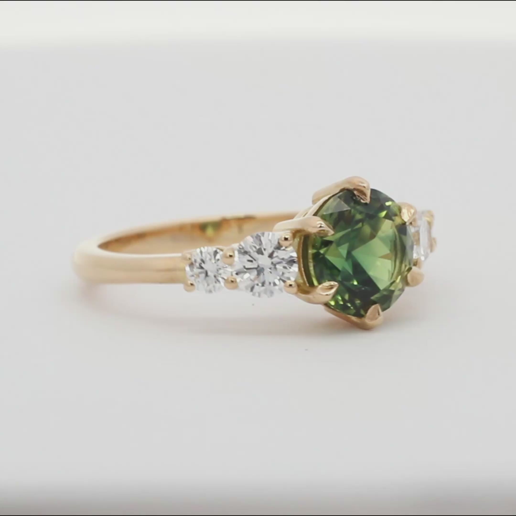 round green blue sapphire engagement ring with round diamonds spinning on a turntable