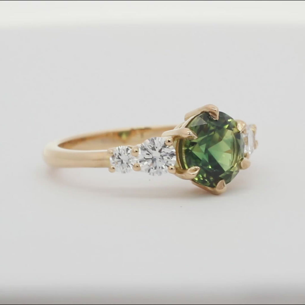 round green blue sapphire engagement ring with round diamonds spinning on a turntable