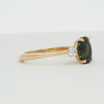 green stone engagement ring with oval sapphire and round diamonds spinning on a turntable