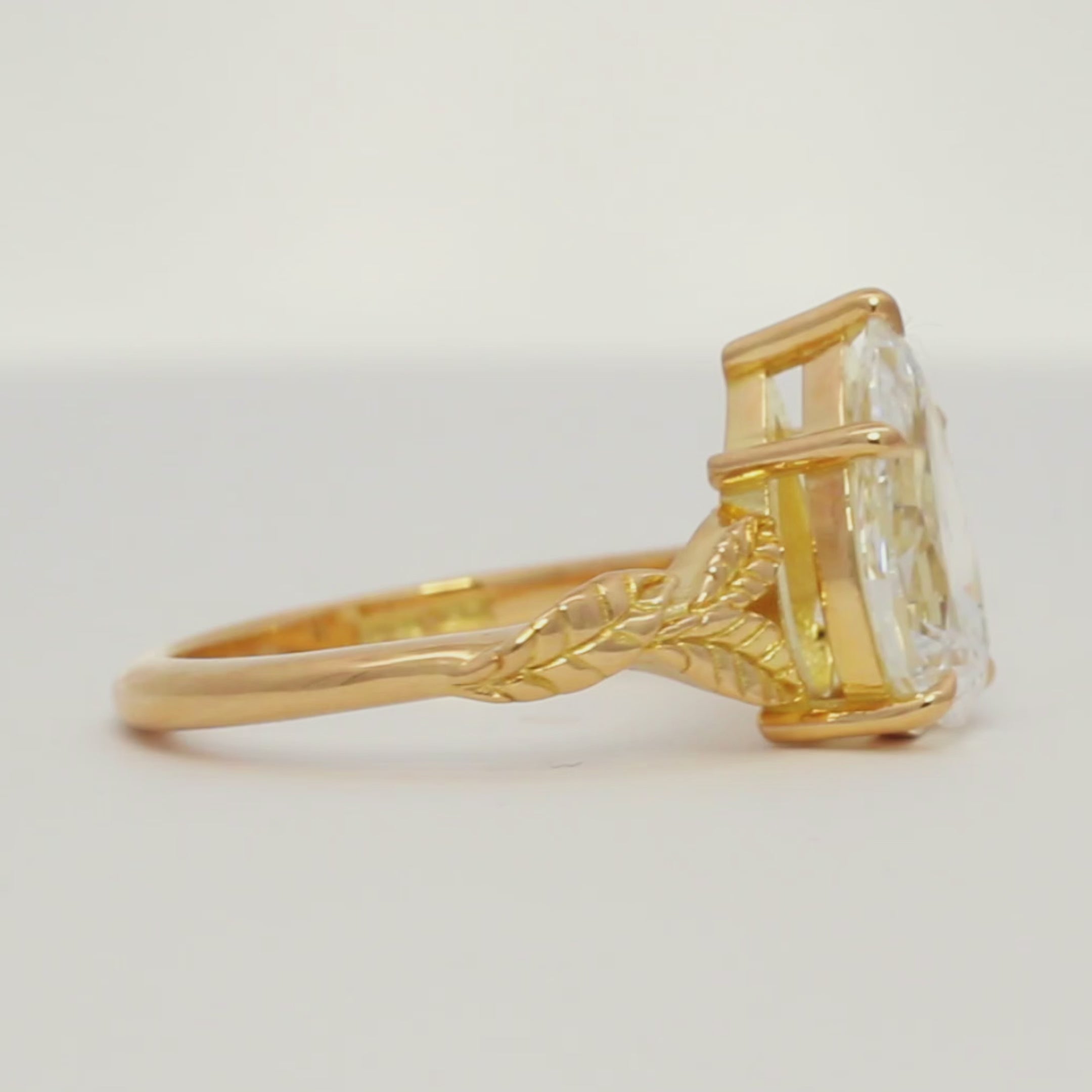 large pear diamond engagement ring with leaf detail spinning on a turntable