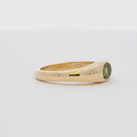 yellow gold band ring with oval green sapphire spinning on a turntable