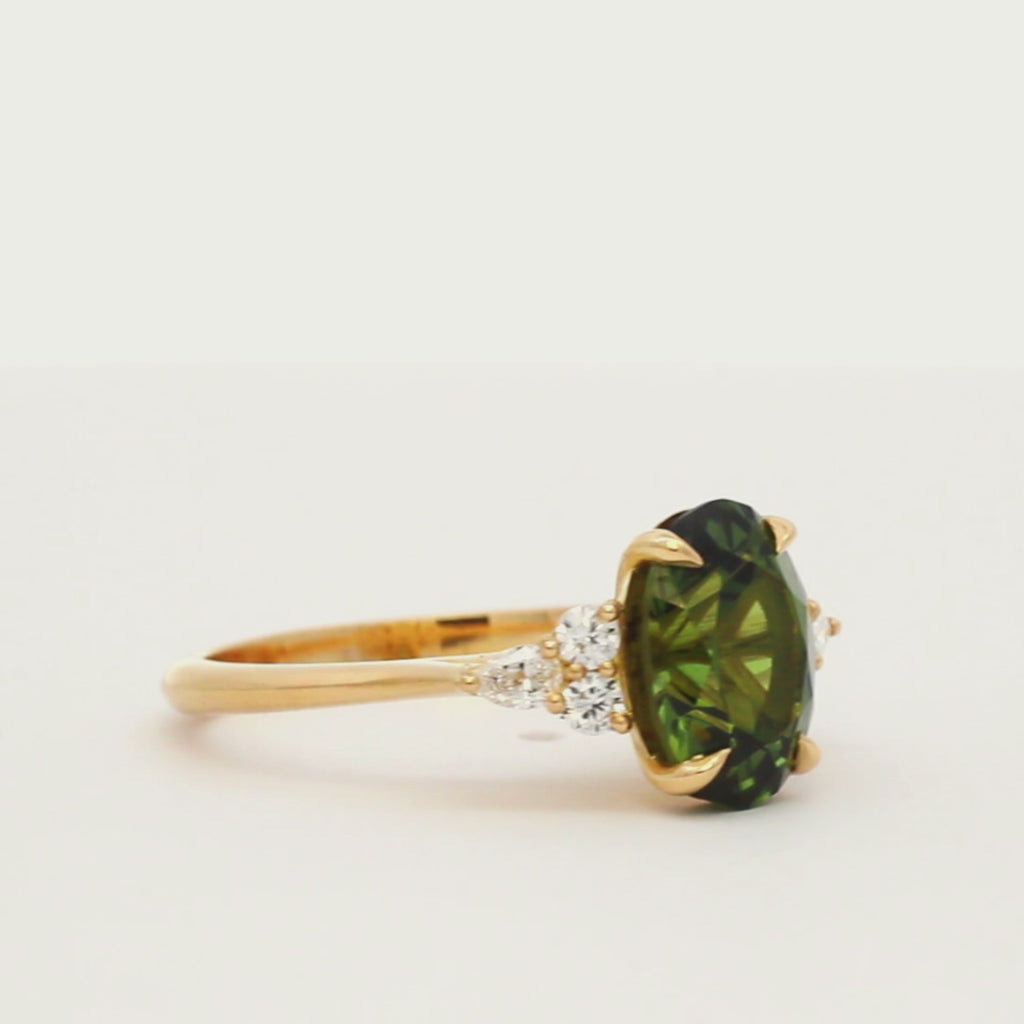 engagement ring with small diamonds and large green sapphire spinning on a turntable