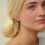 woman wearing diamond stud earring with star and drop dangle looking and smiling at camera