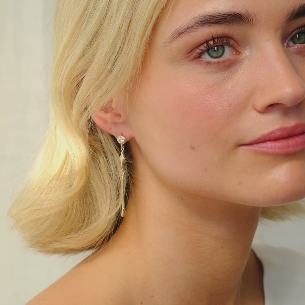 woman wearing diamond stud earring with star and drop dangle looking and smiling at camera
