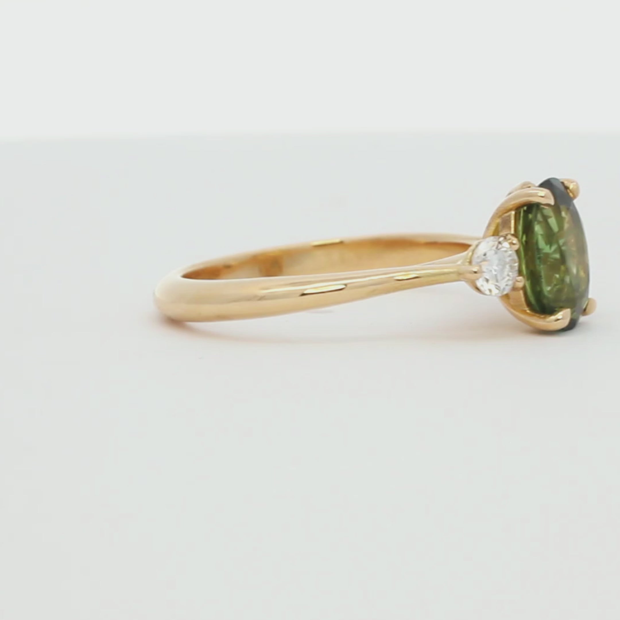 green oval sapphire three stone ring with diamonds spinning on a turntable