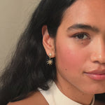close up of bride wearing halter neck dress and diamond sun dangle earrings in gold smiling to camera