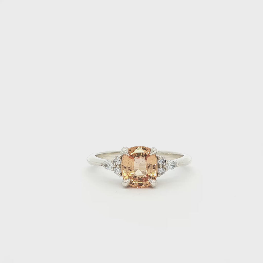 Peachy Orange Sapphire Engagement Ring with Diamonds spinning on turntable