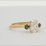 oval diamond and green gemstone ring spinning on a turntable
