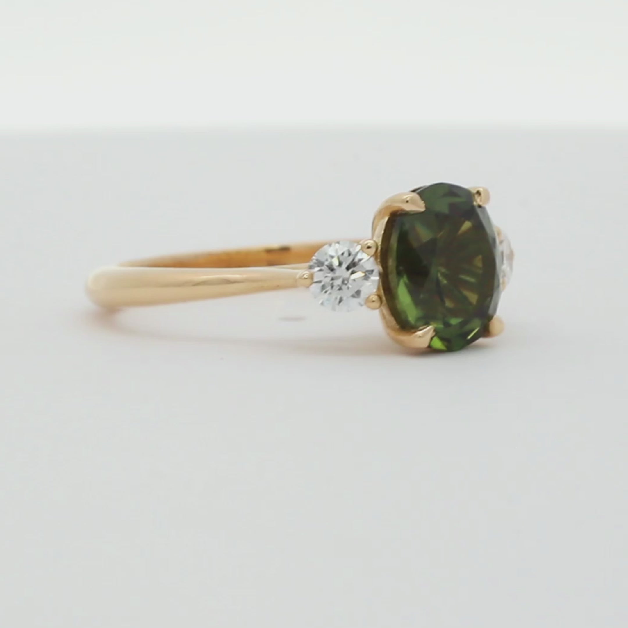 large rounded-oval sapphire engagement ring with round diamonds spinning on a turntable