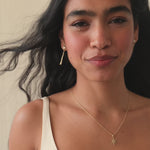 bride with black wavy hair wearing diamond dangle earrings with her hair blowing in the wind