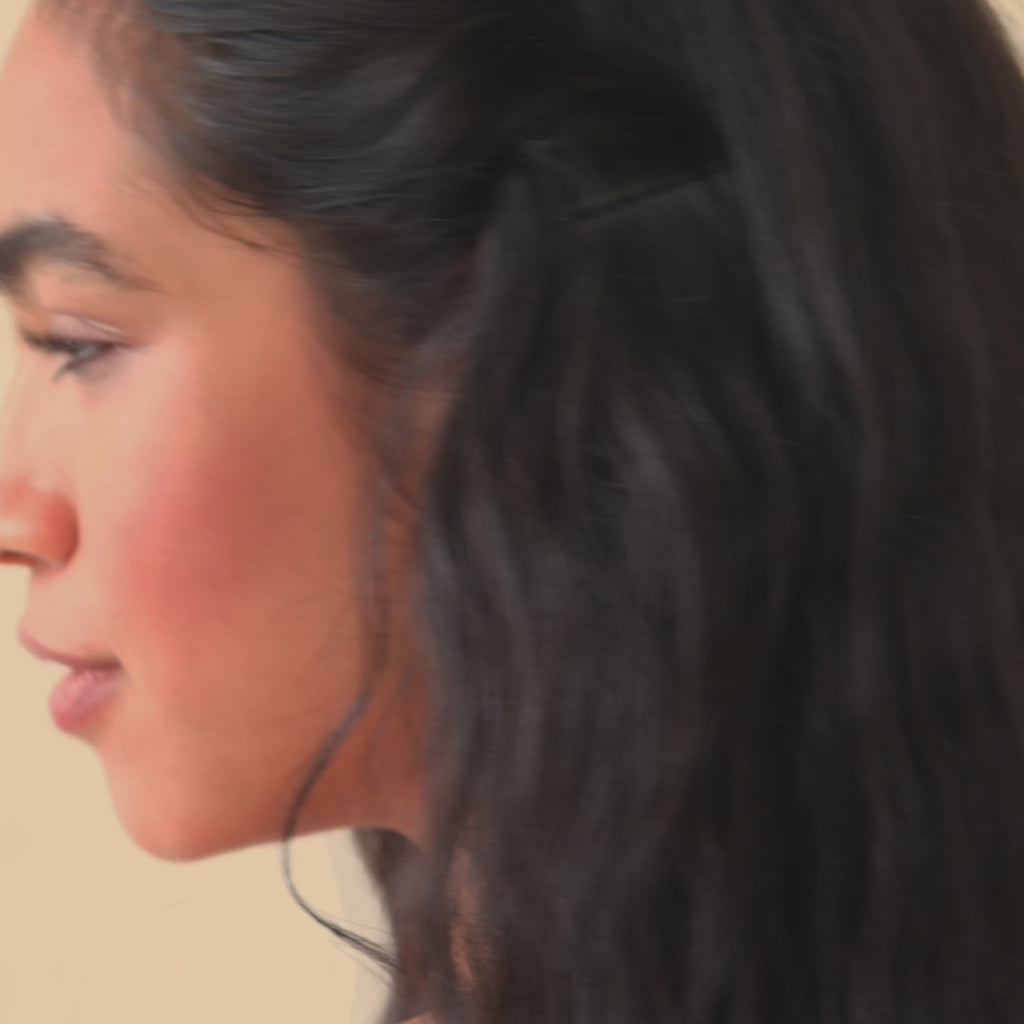 woman with long black hair wearing star shaped stud earrings turning around and smiling to camera