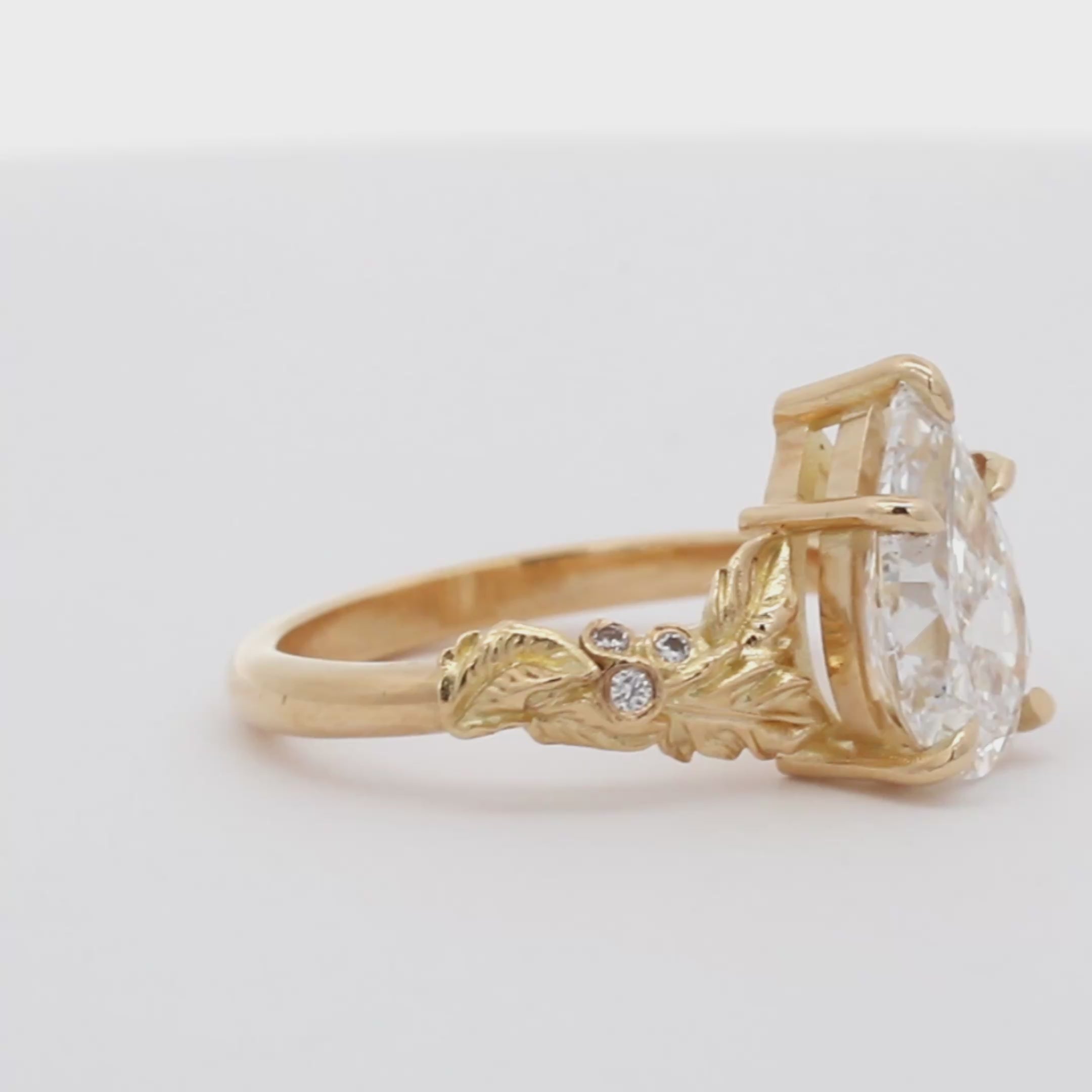 gold diamond pear engagement ring with leaves spinning on a turntable