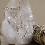 heart silver necklace on a white crystal with sage