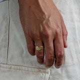 male hand wearing a wide gold ring with textured finish