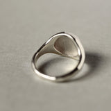 back view of silver signet ring on beige surface