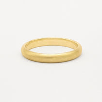 Gold wedding ring with soft satin texture finish on a white background