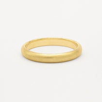 Gold wedding ring with soft satin texture finish on a white background