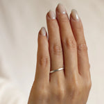 Hand wearing a 2mm flat satin finish wedding ring in white gold on a neutral background