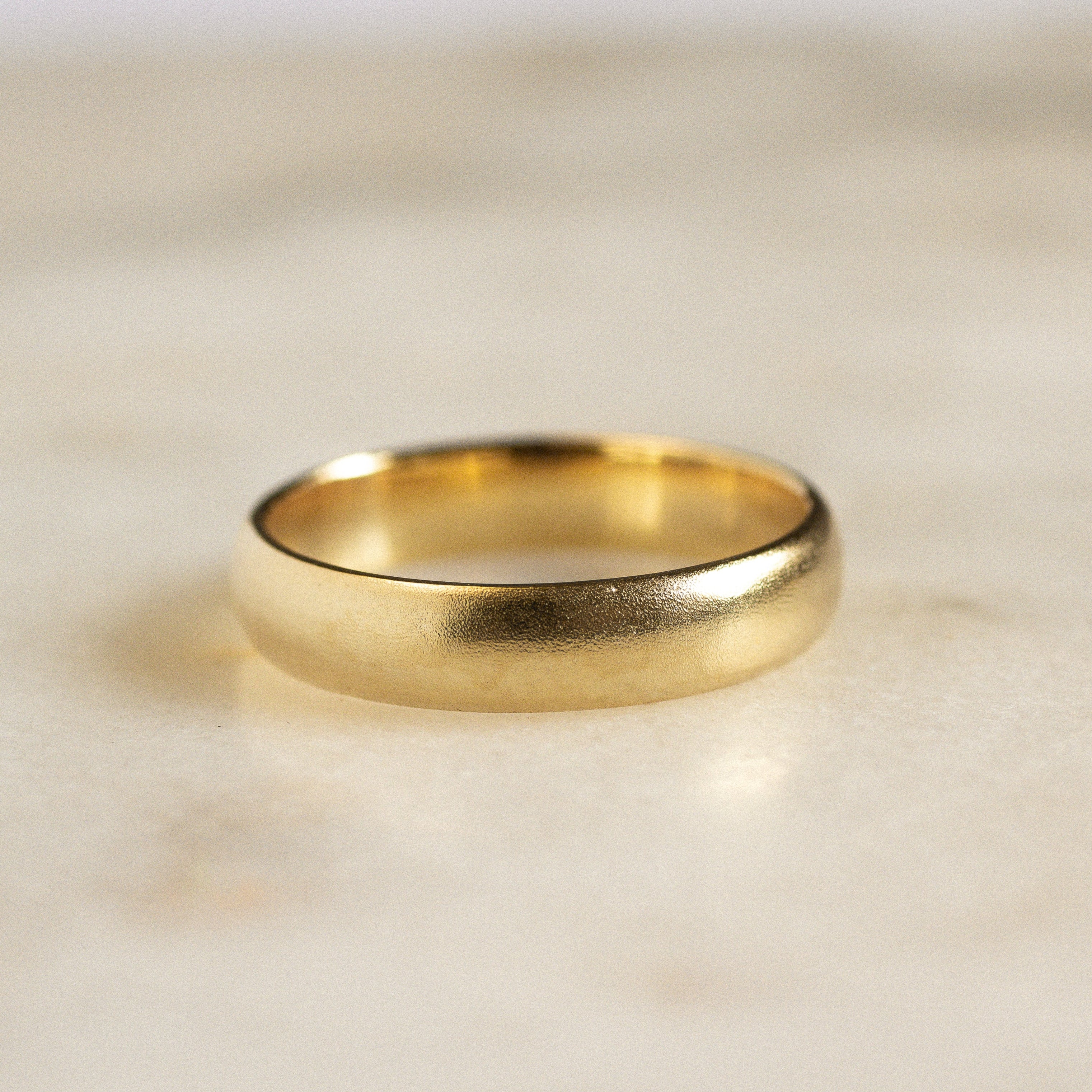 wedding ring with blurred satin finish on marble surface