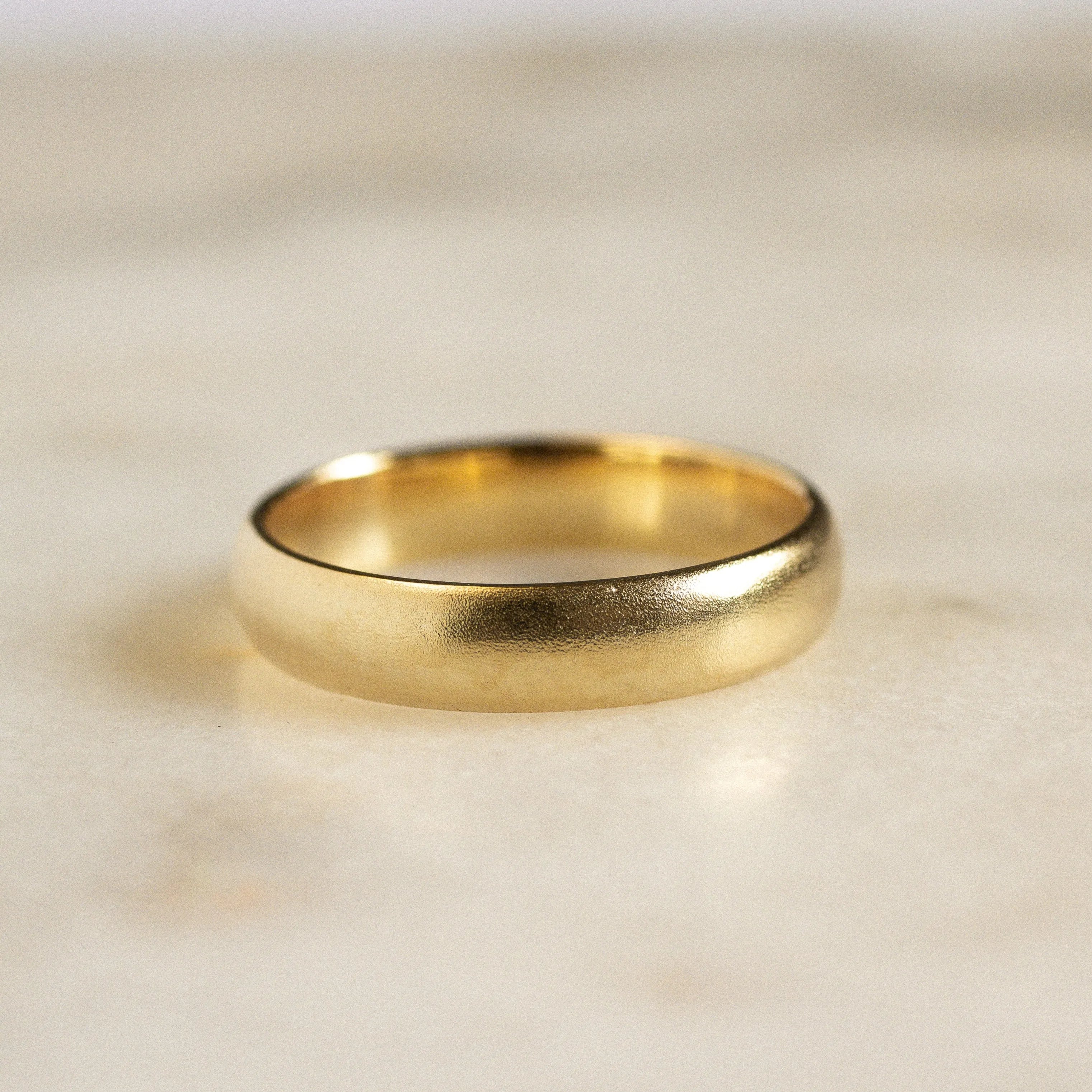 wedding ring with blurred satin finish on marble surface
