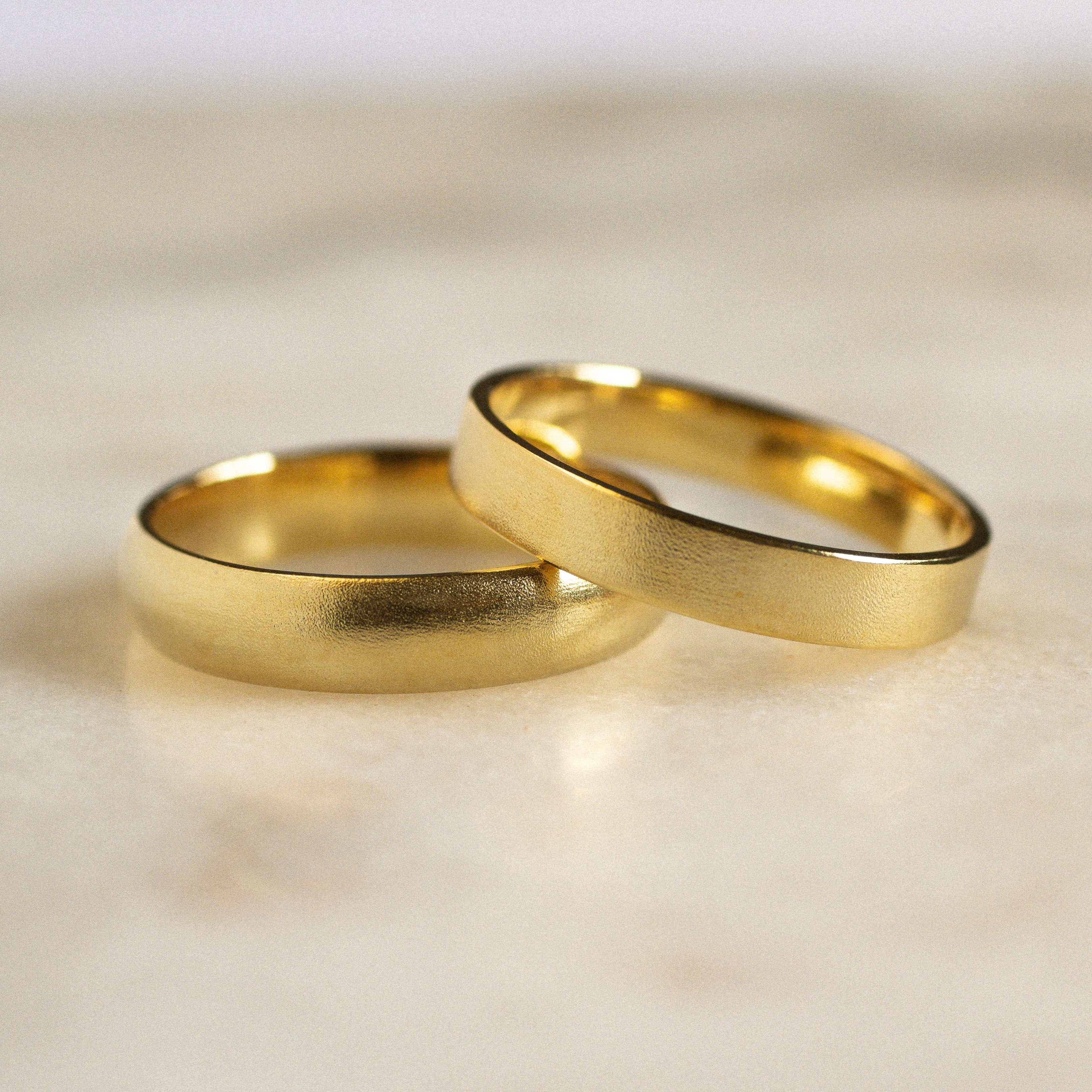a d shape and flat wedding ring with blurred satin finish on marble surface