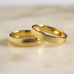 a d shape and flat wedding ring with blurred satin finish on marble surface