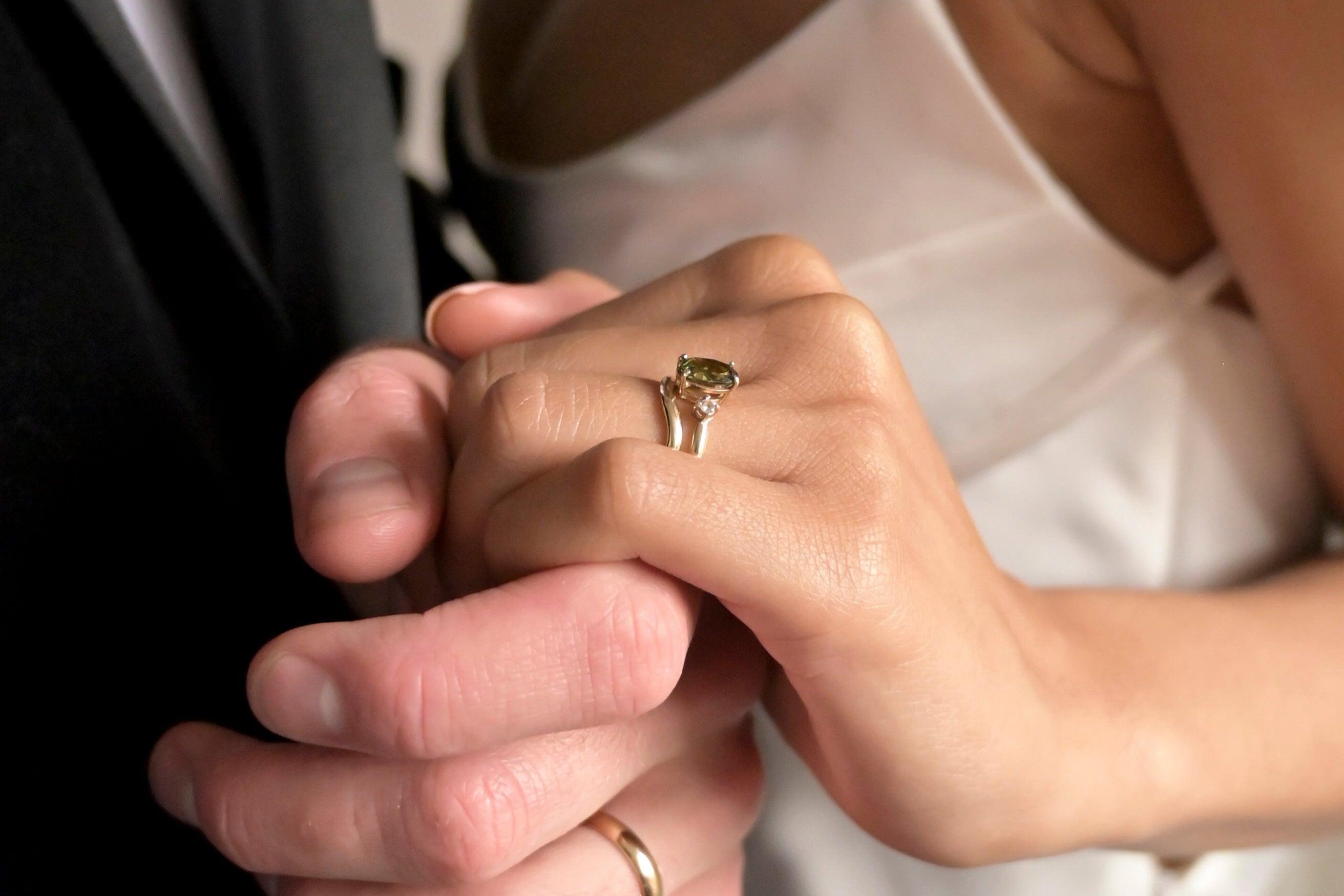 Close-up of hands holding together with wedding rings on a blurred background