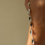 close up of silver chain leaf necklace hanging on arm