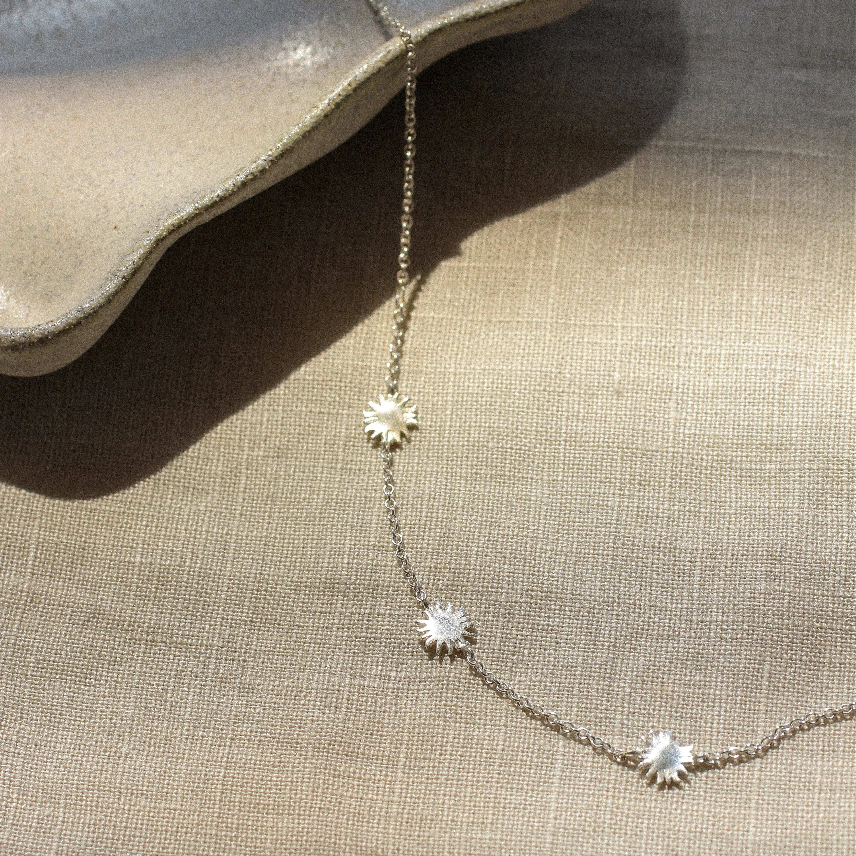 Necklace with star-shaped pendants on a beige fabric background