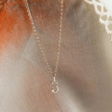 silver number necklace 3 on neutral fabric with warm candle light 