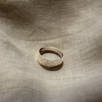 Silver ring on a textured beige fabric surface