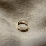 Silver ring on a textured beige fabric surface