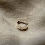 Silver ring on a textured beige fabric surface
