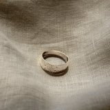 Silver ring on a textured beige fabric surface