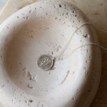 silver st christopher necklace with a round pendant on a textured stone surface