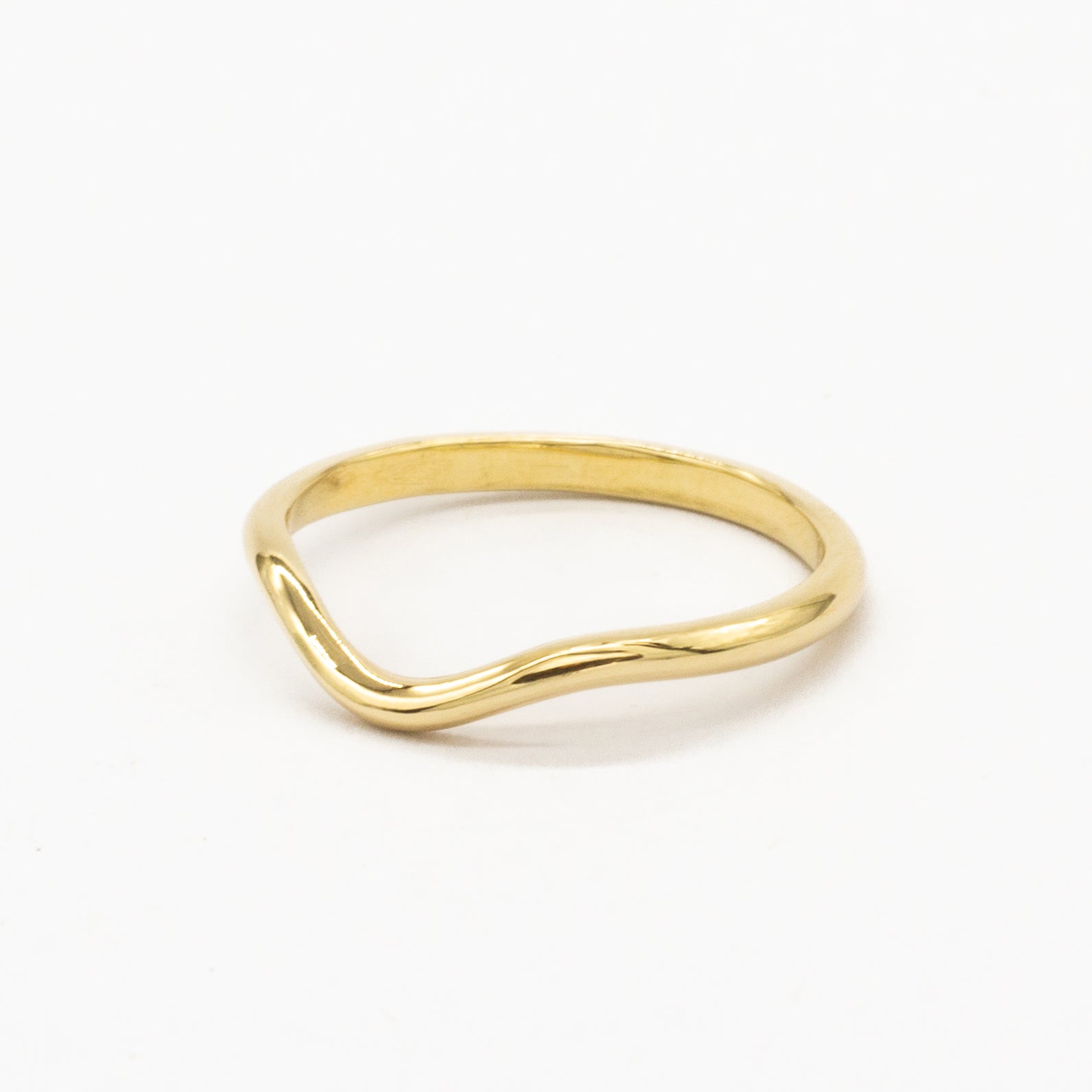 side angle of a softly curved gold wedding ring on a white background