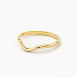 side angle of a softly curved gold wedding ring on a white background