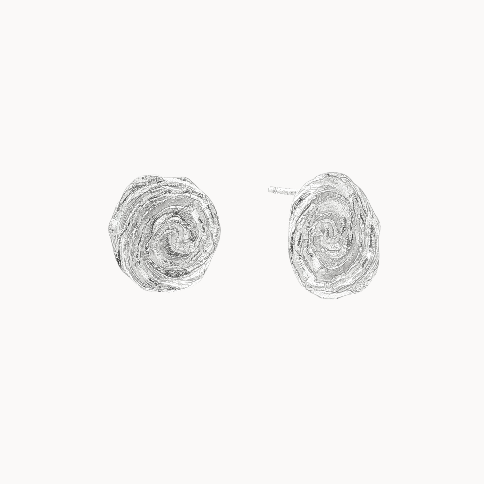 spiral stud earrings in silver with the right outturned revealing the ear pin against a plain off-white background